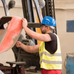 Young worker repairing forklift in her workplace