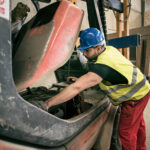 Man repairing forklift in concrete factory